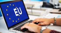 Manos sobre un portátil, donde en la pantalla se muestra la bandera de la UE y las siglas EU