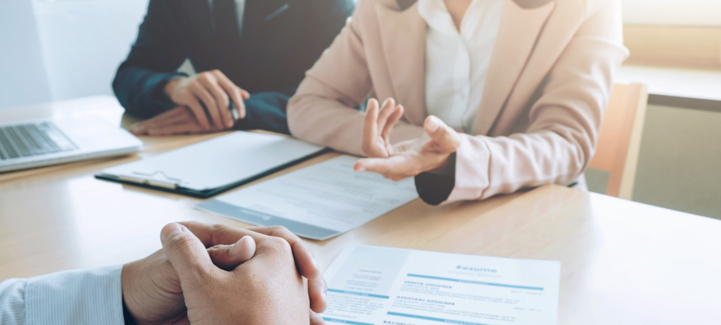 Entrevista de trabajo en una oficina, con un currículum sobre la mesa y personas conversando