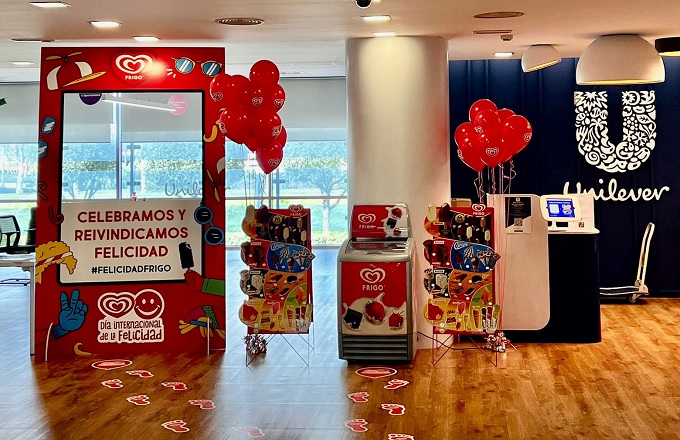 Un photocall de helados frigo, junto a una nevera para helados, dos carteles anunciadores, unos globos y un cajero automático